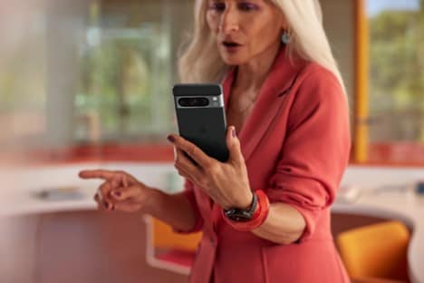 Woman in a pink jacket holding the Google Pixel 8 Pro.