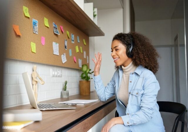 College Student talking via her laptop while wearing headphones.