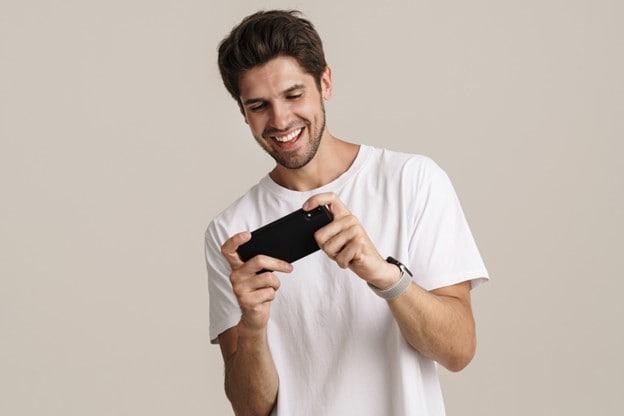 A man holding a cell phone enjoying mobile entertainment.