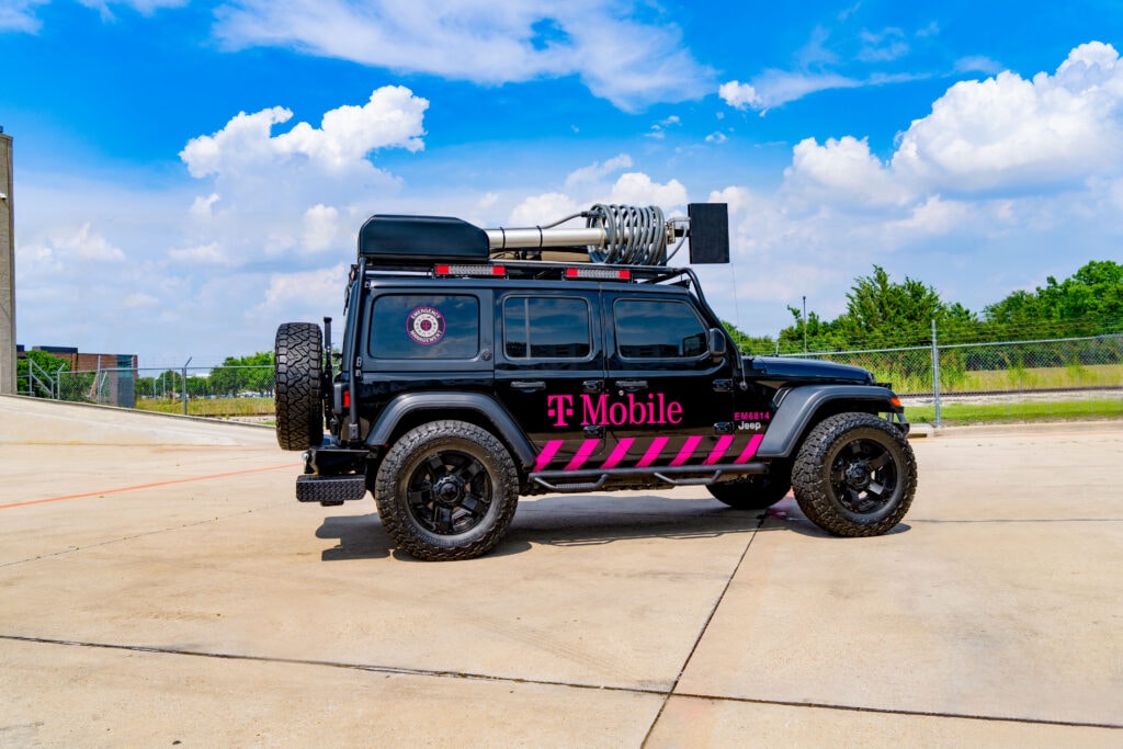 mobile365 logo branded all-terrain vehicle with mounted satellite equipment retracted to convey portability. Vehicle is parked outdoors.